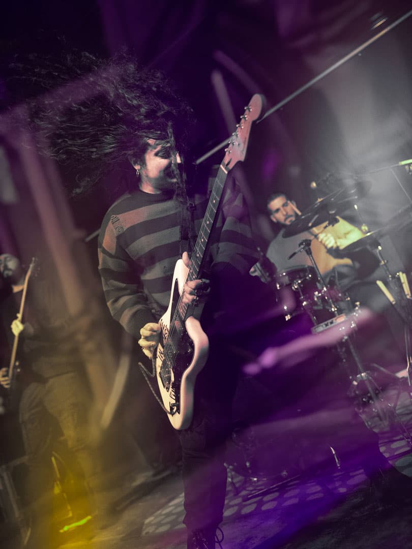 SAYST chitarrista con i capelli lunghi catturato in un momento di pura energia rock